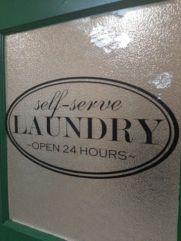 a silver wall with a sign forjl service laundry open 24 hours