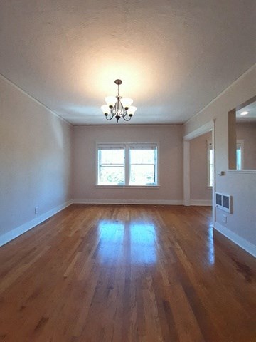 an empty living room with a wood floor and a chandelier