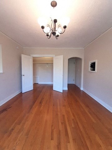 an empty living room with a wooden floor and a chandelier