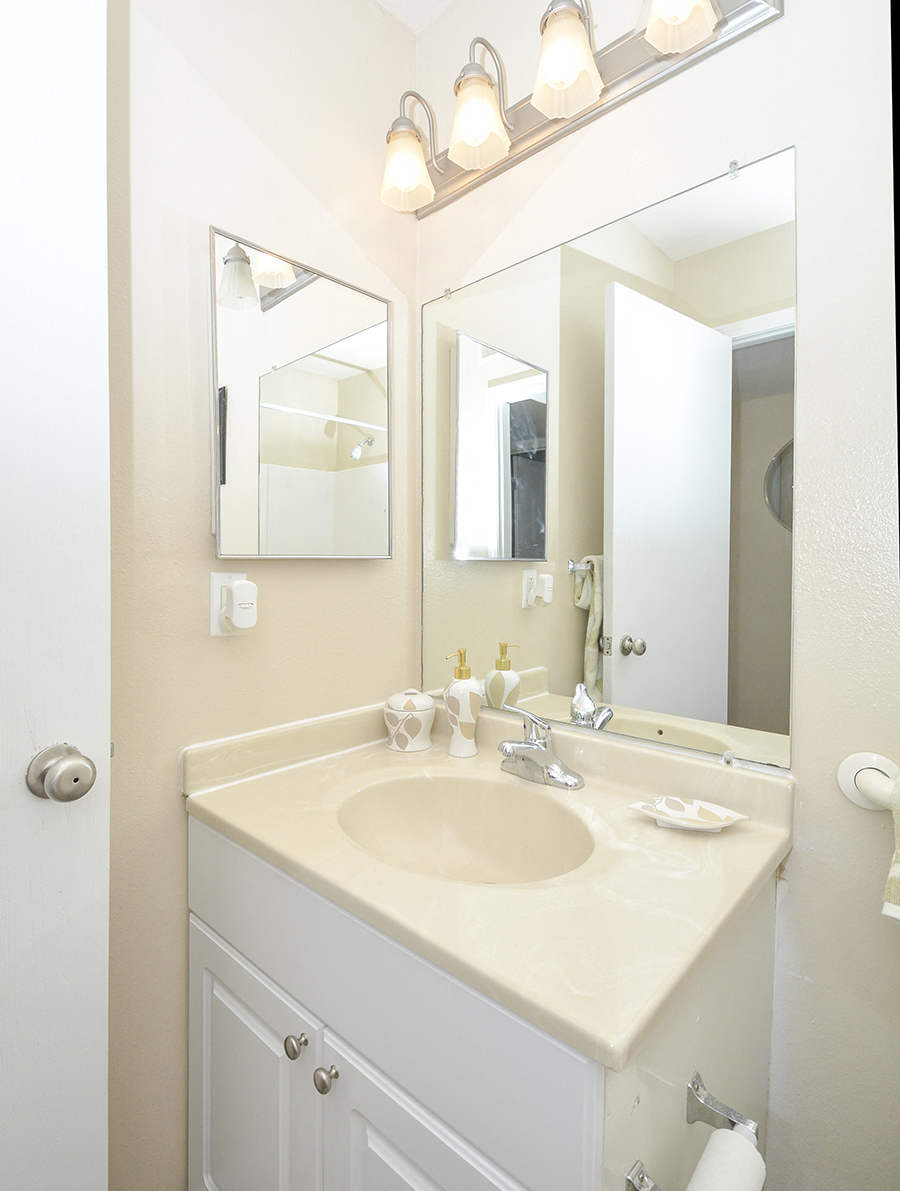 White Bathroom Vanity with Beige Countertop and Large Mirror