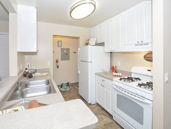 Galley Kitchen with White Cabinetry and Appliances