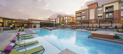 a large swimming pool with lounge chairs in front of apartment buildings