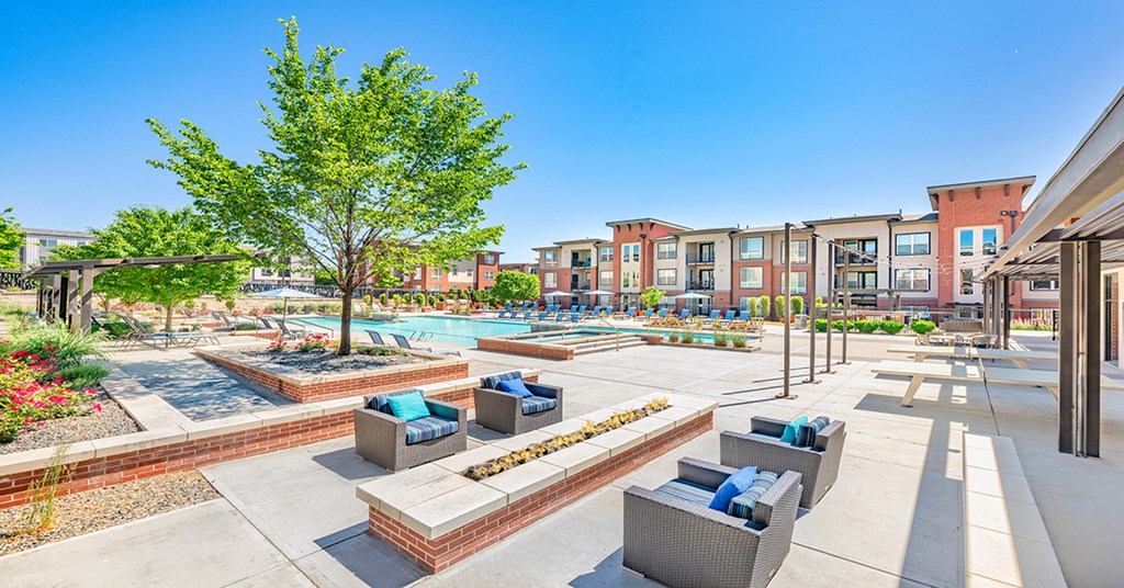 A sunny day at a residential complex with a pool and lounge chairs.