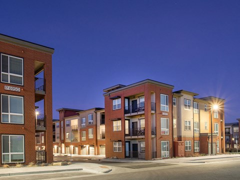 a row of brick apartment buildings lit up at night
