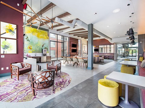 a large lobby with tables and chairs and a large painting on the wall