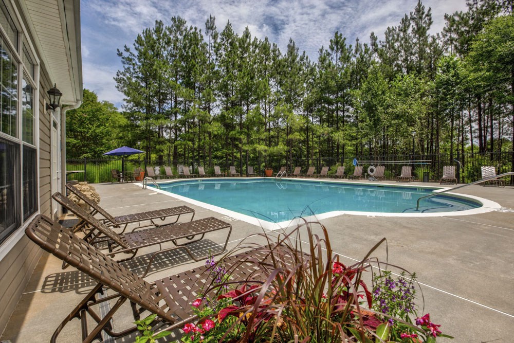 the pool is next to the house with chairs and plants