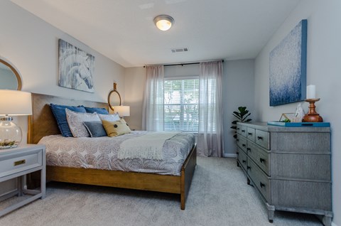 a bedroom with a bed and a dresser and a window