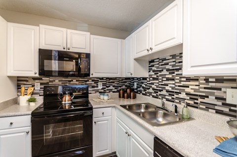 a kitchen with white cabinets and black appliances and a sink