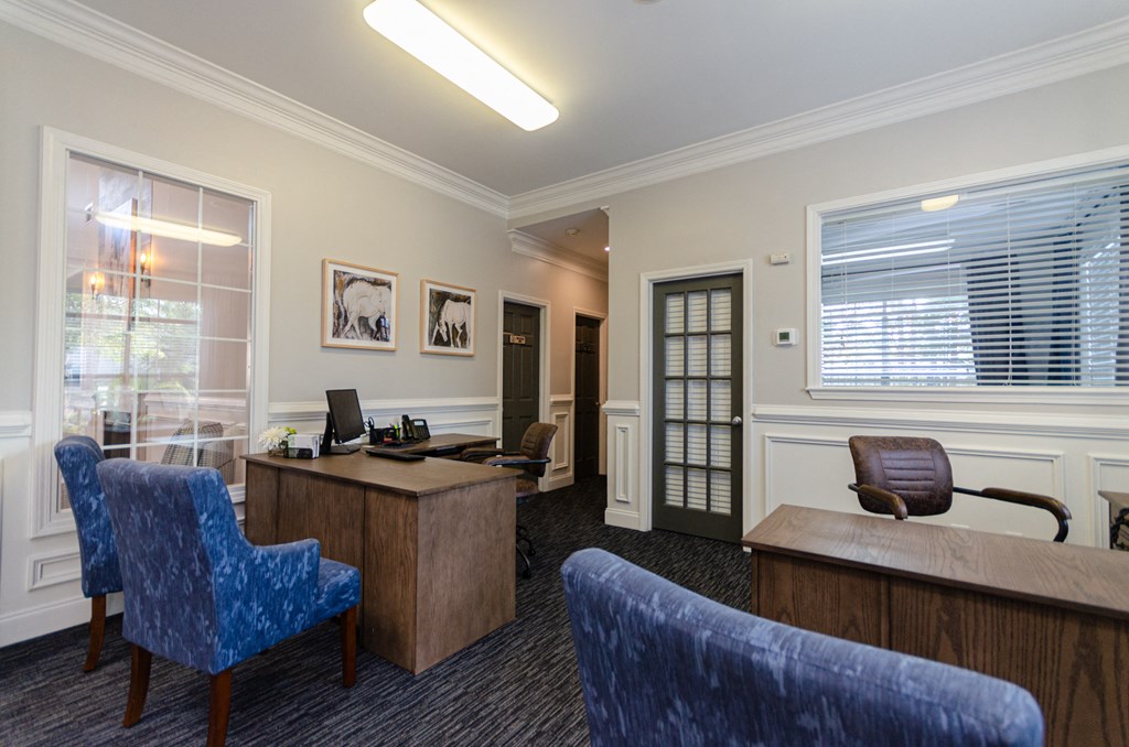an office with a desk and chairs and a window