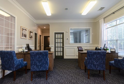 an office with blue chairs and a desk and a window