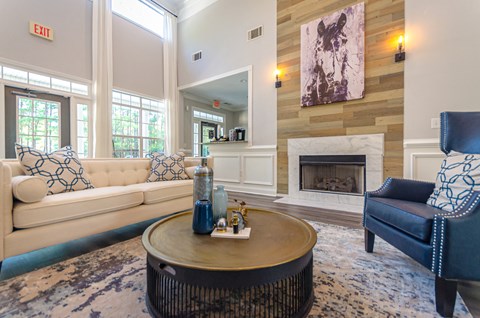 the living room has a fireplace and blue chairs and couches