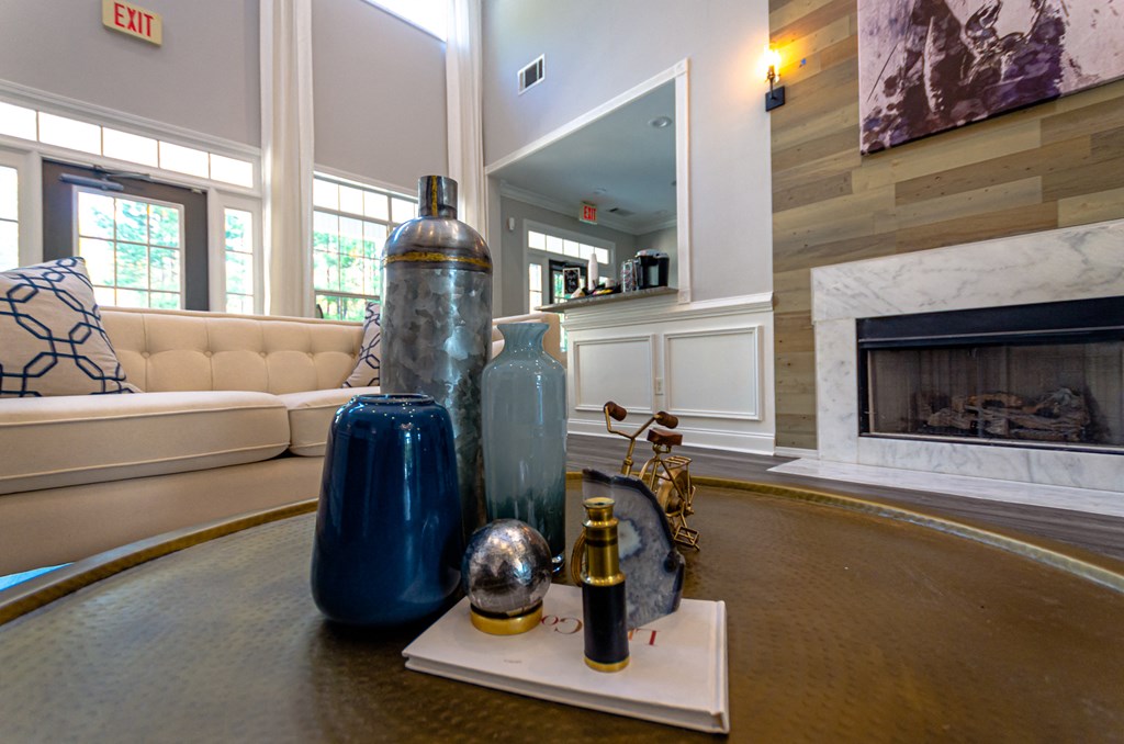 a living room with a table with vases and a fireplace