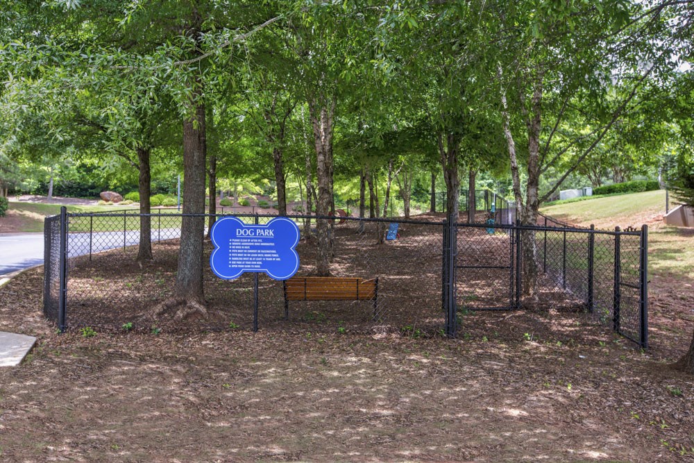 a park with a bench and trees and a blue sign