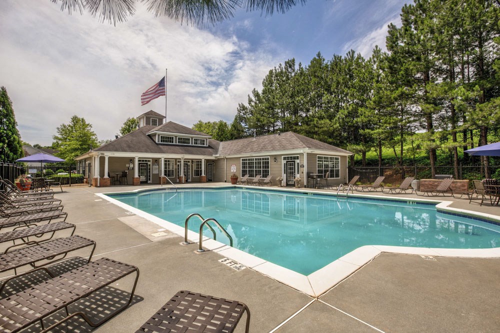 a swimming pool with chairs and a house in the background