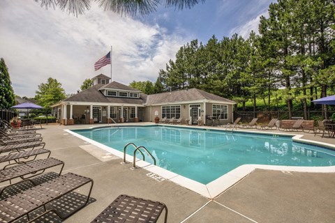 a swimming pool with chairs and a house in the background