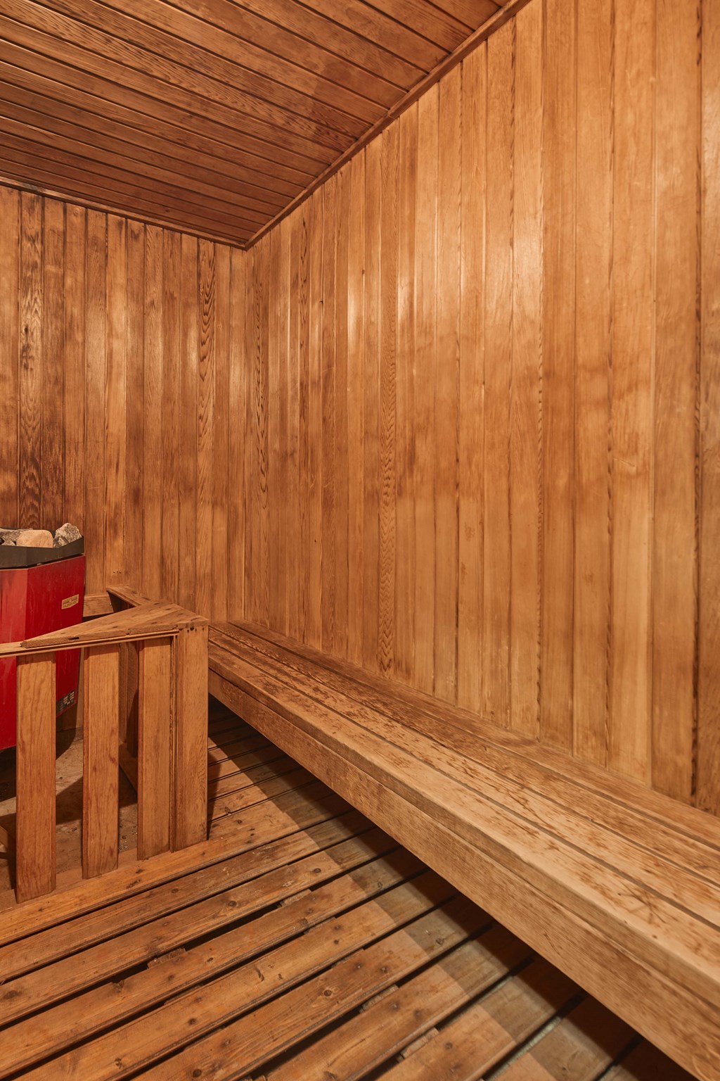 a wooden sauna with a wooden bench and a red fire extinguisher
