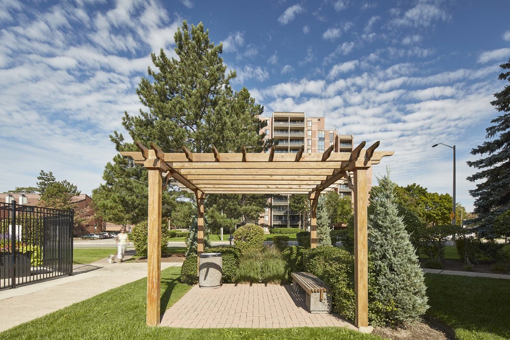 a wooden pergola over a brick patio in a park