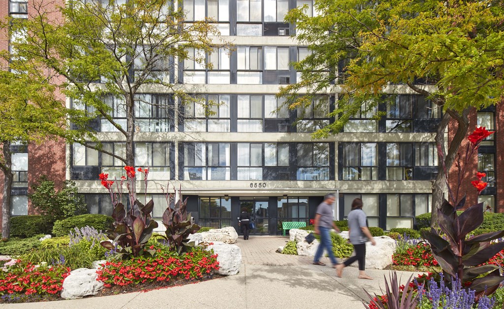 people walking in front of an office building with plants and flowers