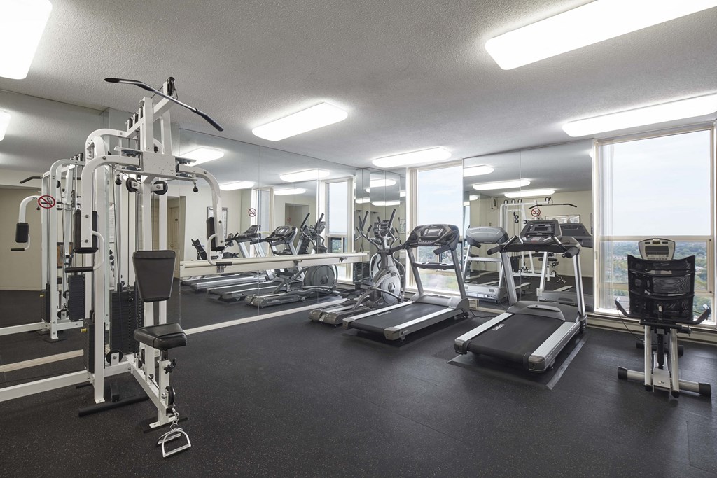 a gym with cardio equipment and windows in a building