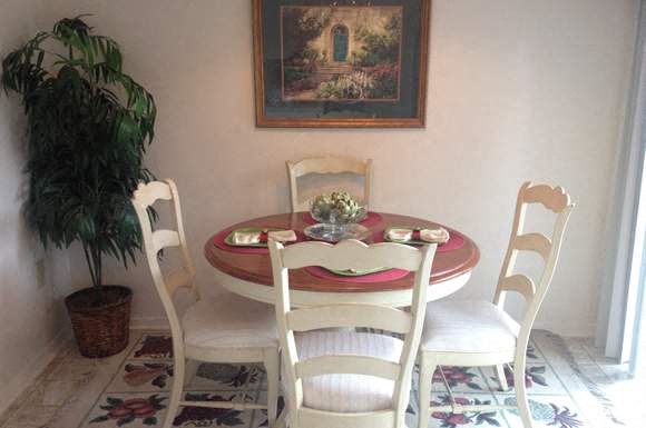 a dining room table with four chairs and a painting on the wall