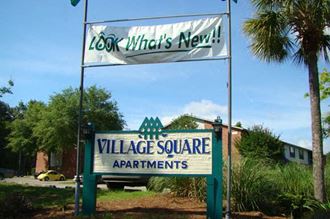 a sign in front of a building that says village square apartments