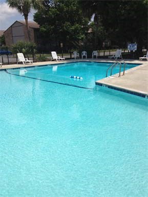 a large swimming pool with blue water and white chairs
