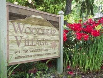 a wooden sign in a garden with red flowers