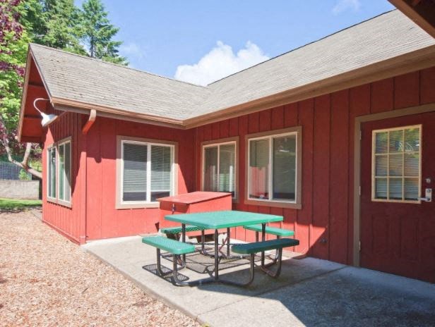 A red building with a green picnic table in front.