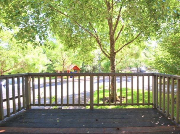A wooden deck with a railing and a tree in the middle.
