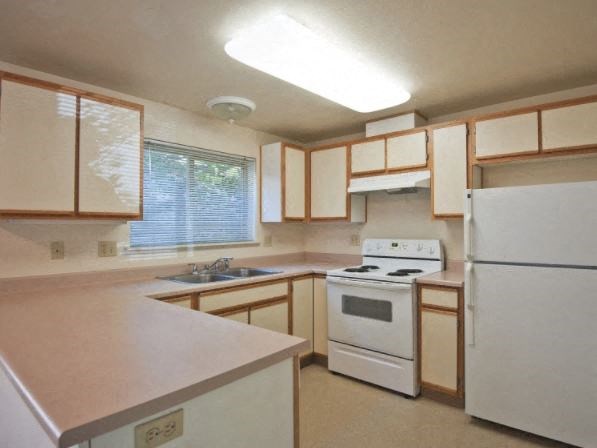 A kitchen with white appliances and wooden cabinets.