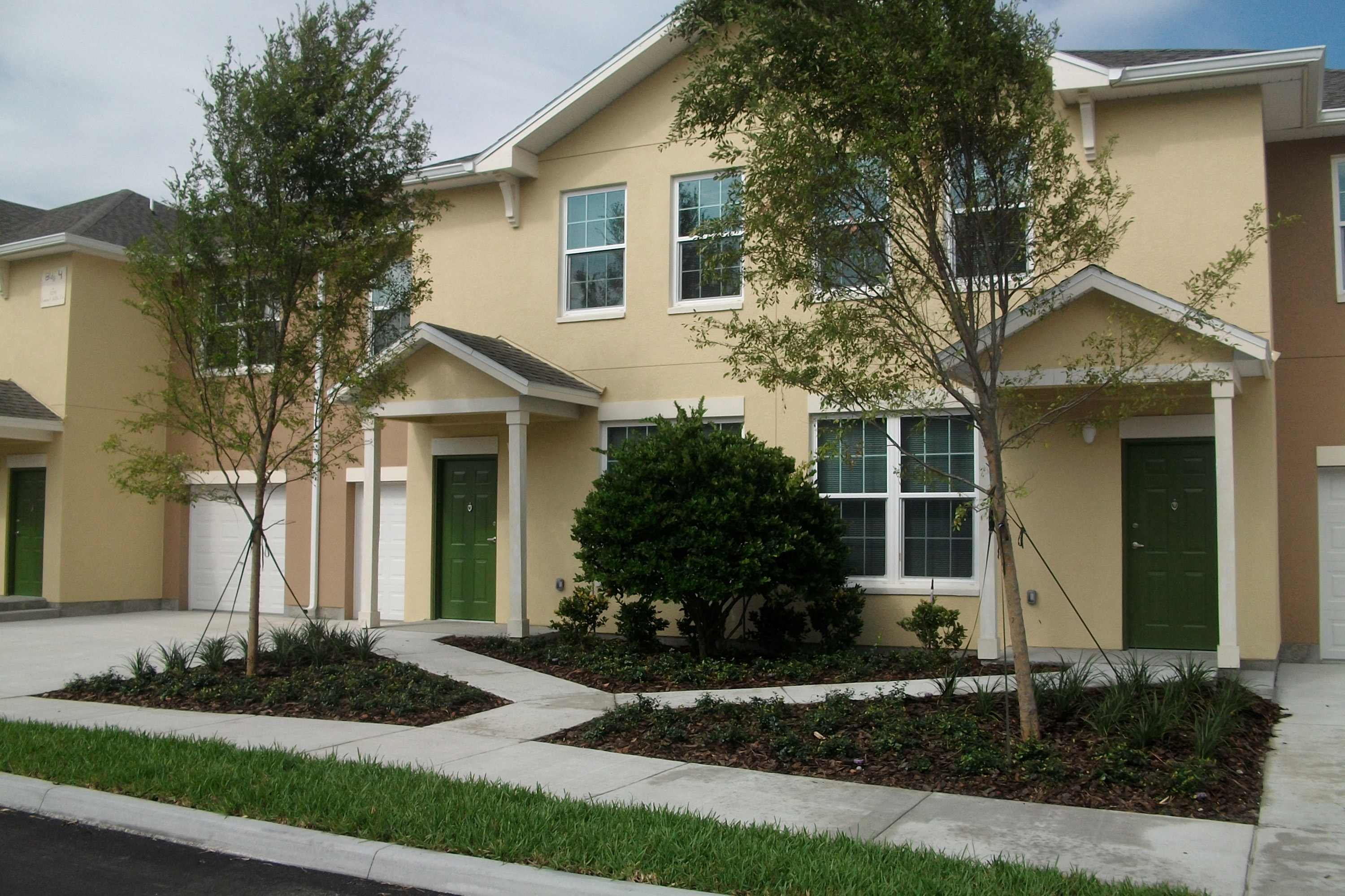 a house with a sidewalk and trees in front of it