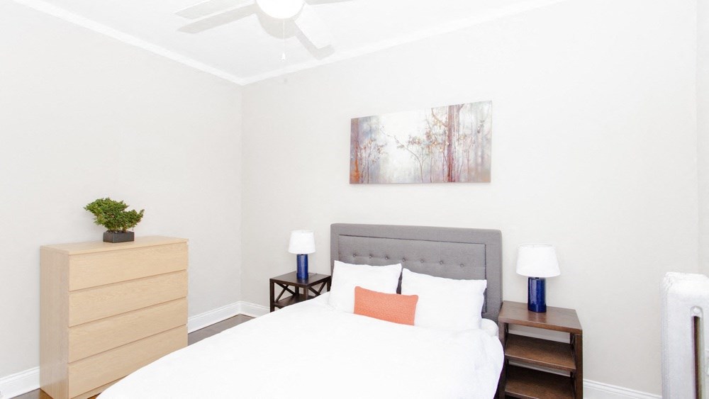 a bedroom with a white bed and a painting on the wall