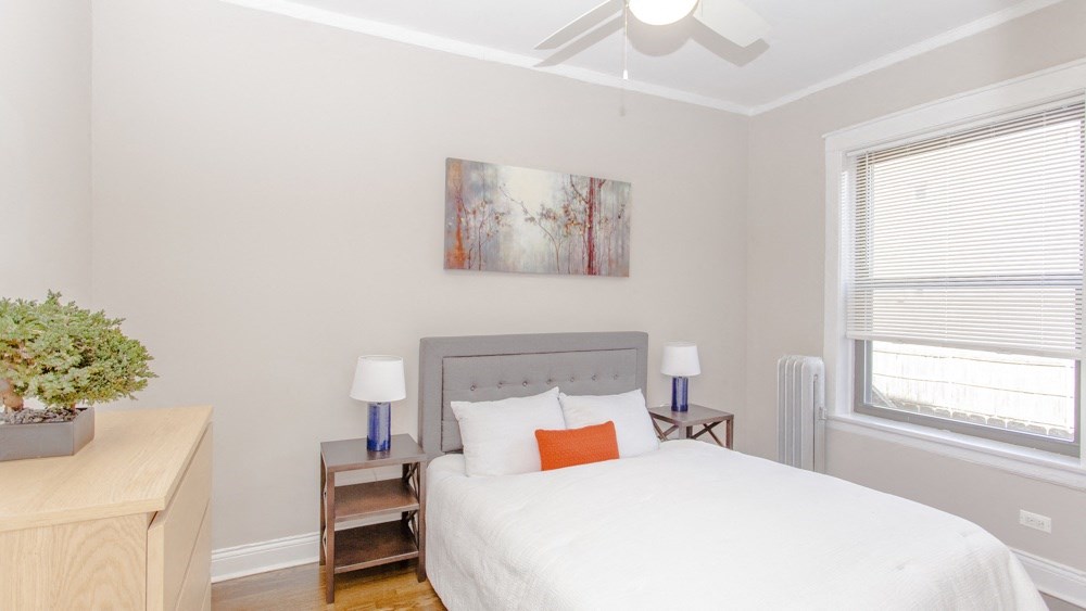 a bedroom with a white bed and a ceiling fan