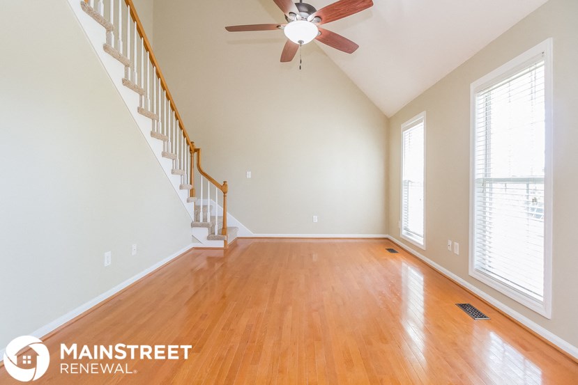 an empty living room with a staircase and a ceiling fan