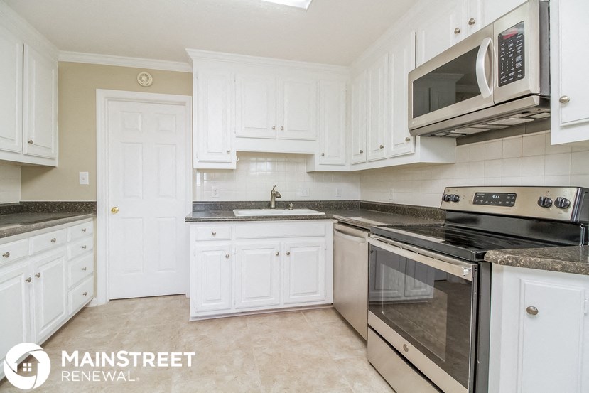 a kitchen with white cabinets and stainless steel appliances