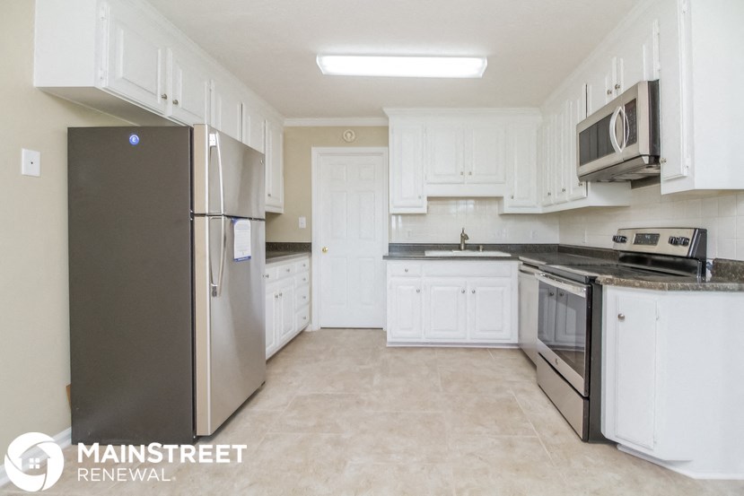 a white kitchen with stainless steel appliances and white cabinets