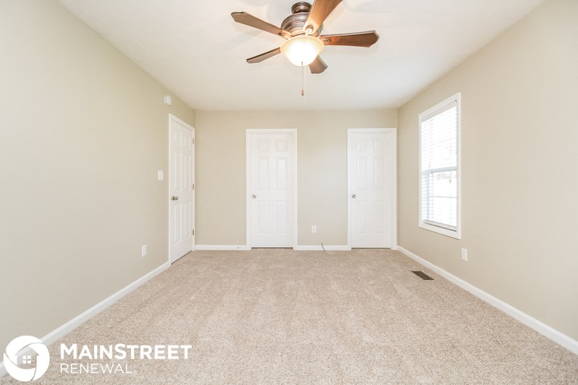 a spacious living room with carpet and a ceiling fan