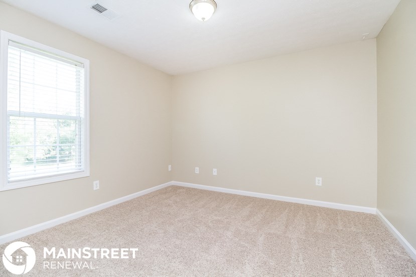 the upstairs bedroom with carpeted flooring and a window
