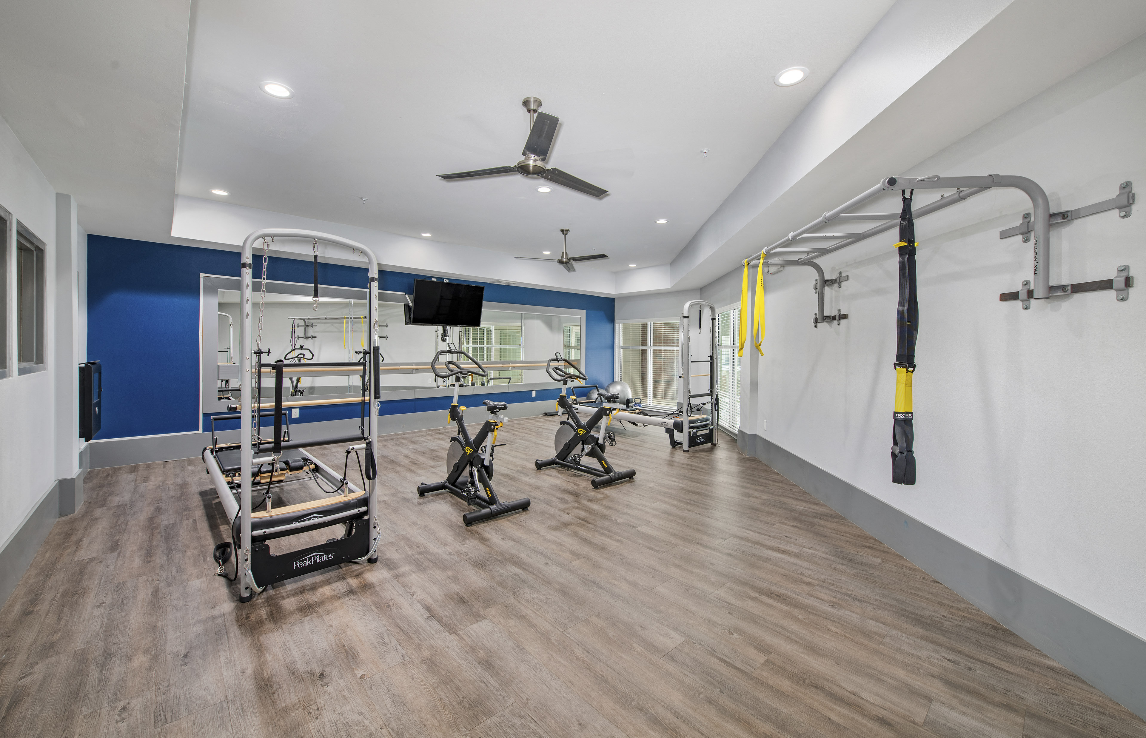 a gym with weights and cardio machines and a wall mounted tv