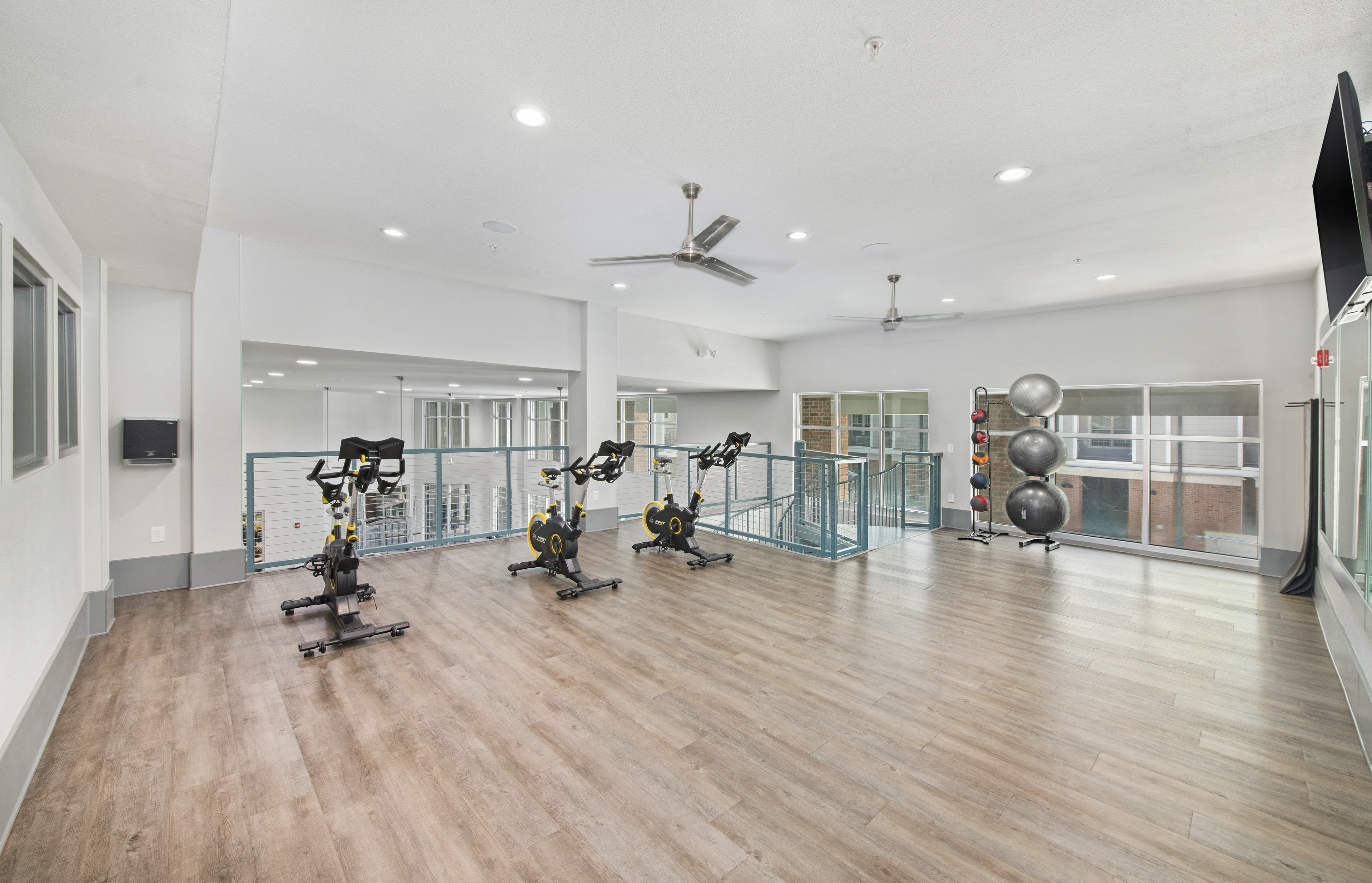 a gym with weights and cardio equipment in a large room with windows