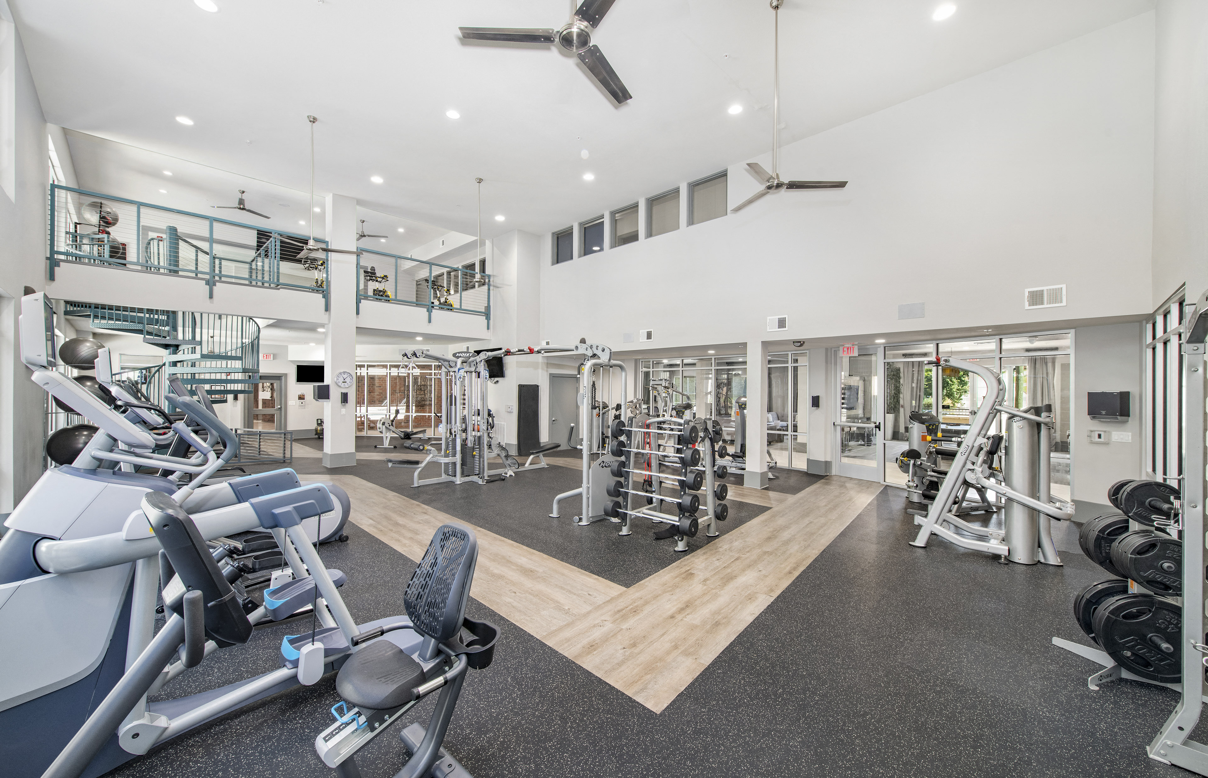 a gym with weights and cardio machines and a staircase