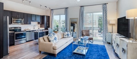 a living room and kitchen with a blue rug and a couch