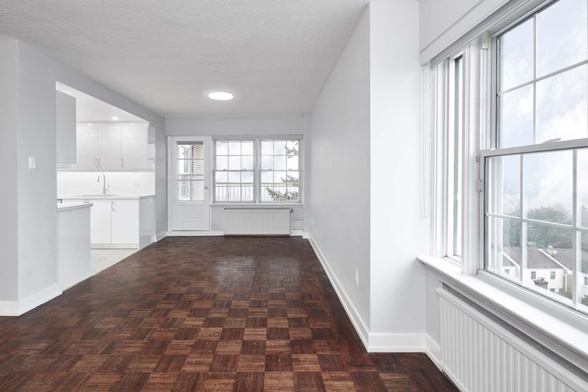 an empty living room with a large window and a kitchen