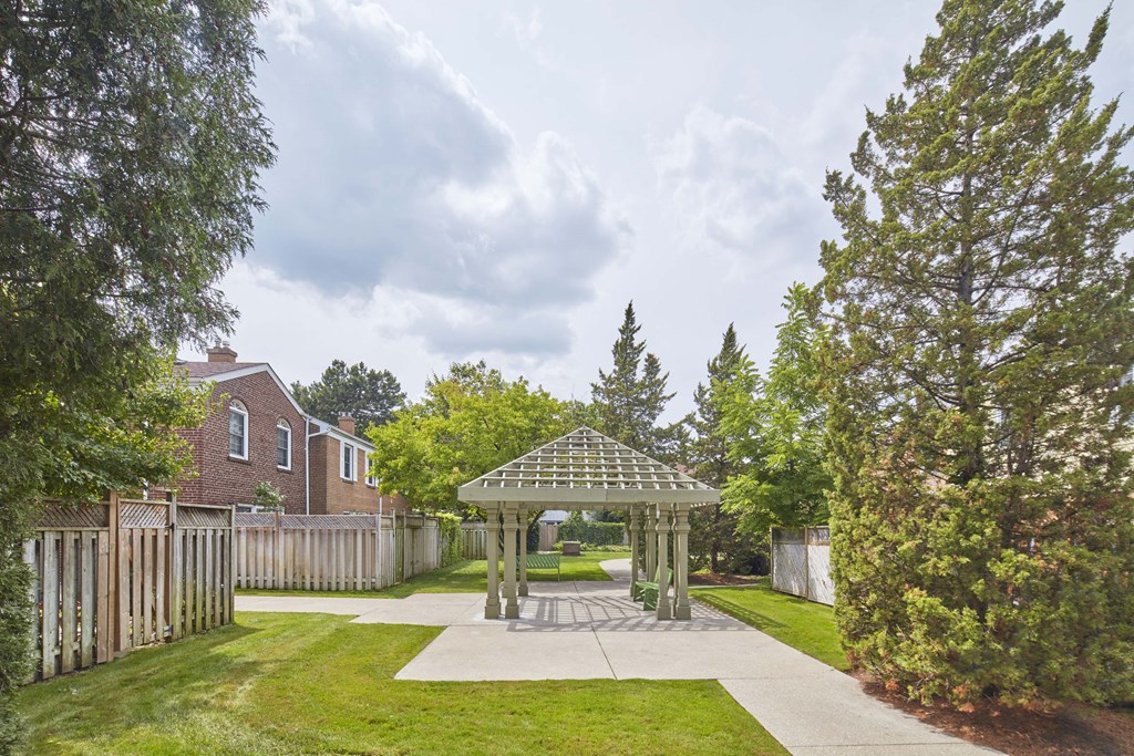 a gazebo in the middle of a yard with a fence and trees