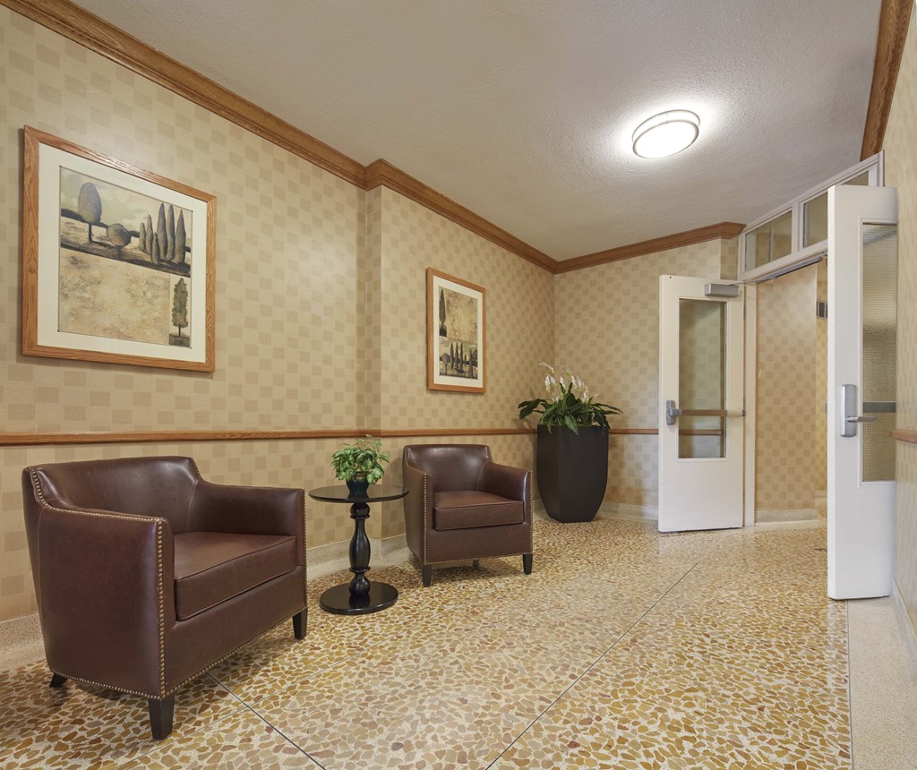 a lobby of a hotel with two chairs and a door