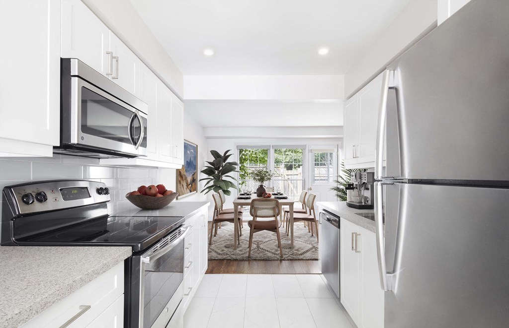 a white kitchen with stainless steel appliances and a dining room