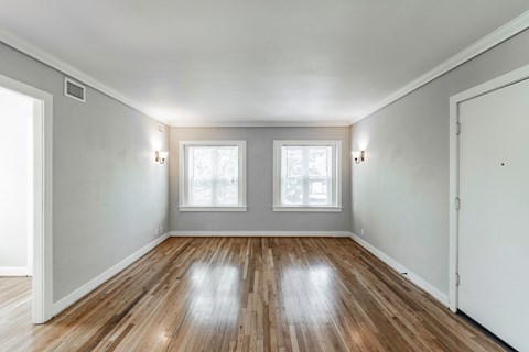 the living room of a house with white walls and wood floors