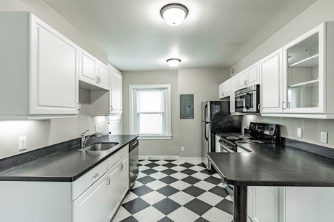 a kitchen with black and white checkered floor and white cabinets