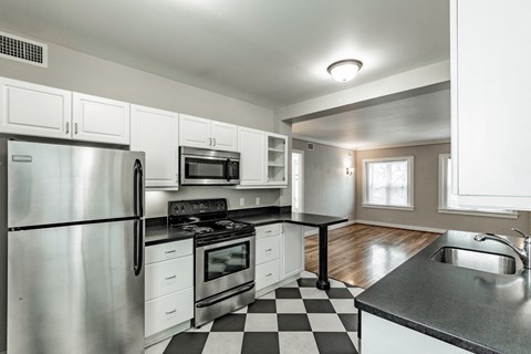 an empty kitchen with stainless steel appliances and a checkered floor