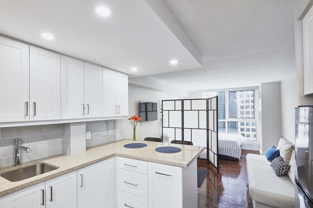 an open kitchen with white cabinets and a living room